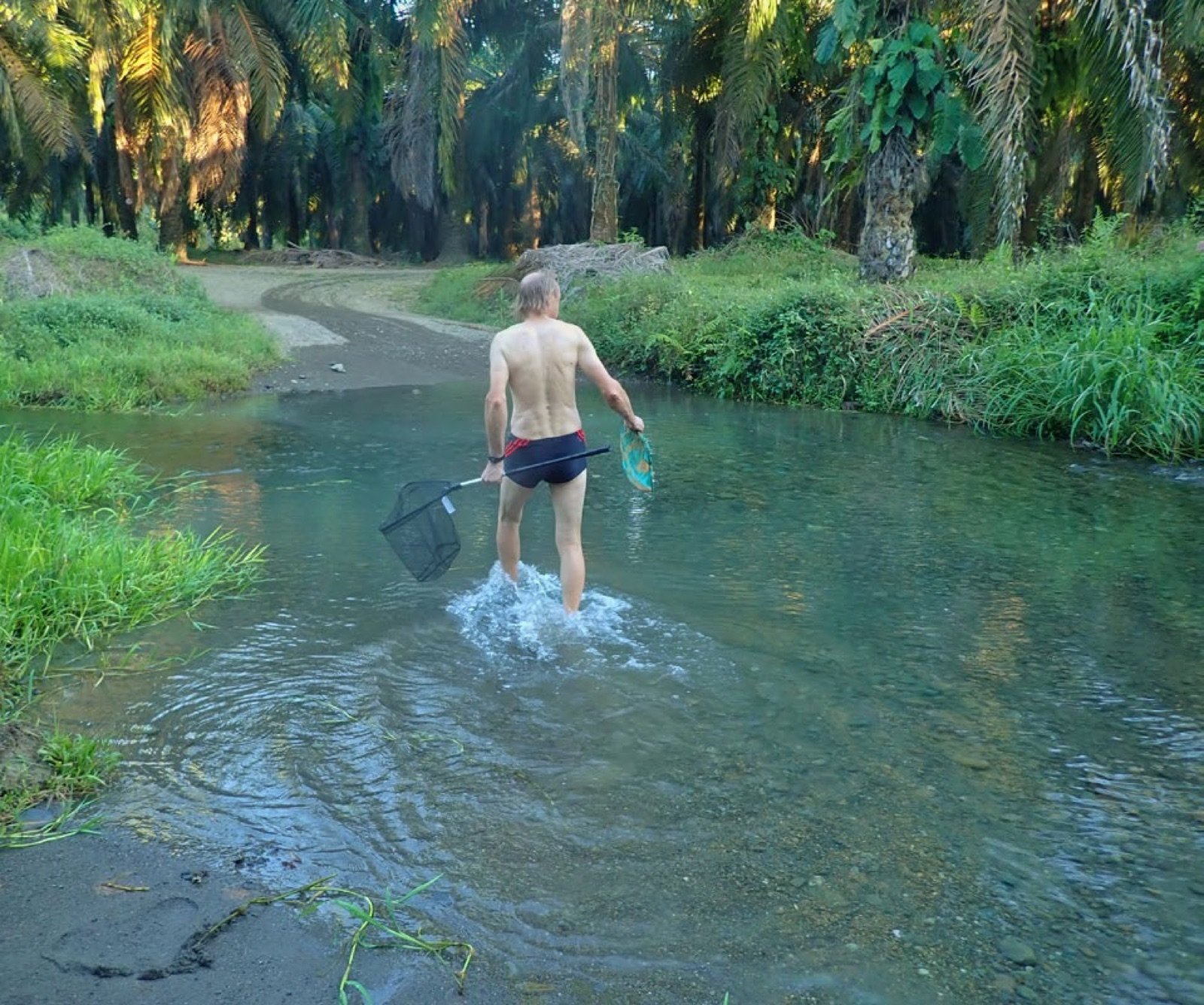 Pêcheur, épuisette et tamis en mains dans le rio Naranjo