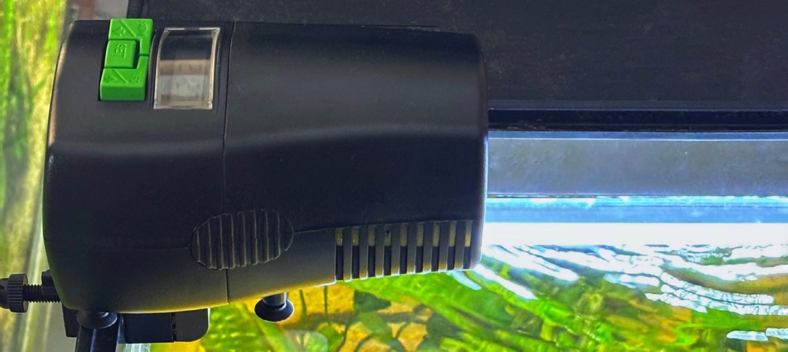Le distributeur myFeeder fixé sur le bord d’une vitre d’aquarium grâce à son support