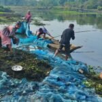 Pêcheurs ramenant un grand filet bleu sur une berge en Inde du nord