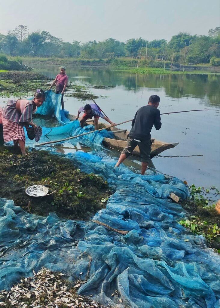 Pêcheurs ramenant un grand filet bleu sur une berge en Inde du nord